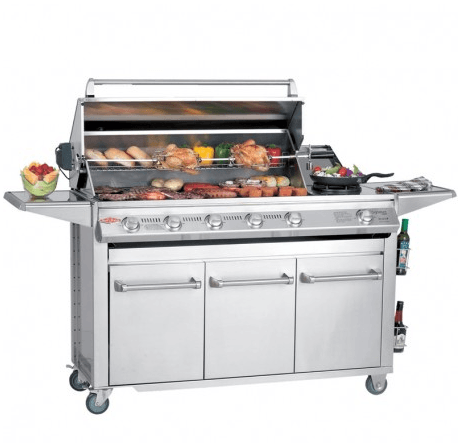 Barbacoa Signature Premium 6B con la tapa abierta mostrando el uso del kit de rosticería y la gran superficie de cocción para eventos en una cocina exterior