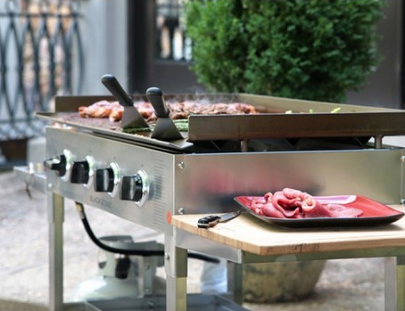 Gran superficie de plancha de acero inoxidable de la BeefEater Clubman en funcionamiento, ideal para cocinar grandes cantidades de alimentos de forma uniforme en clubs sociales o catering