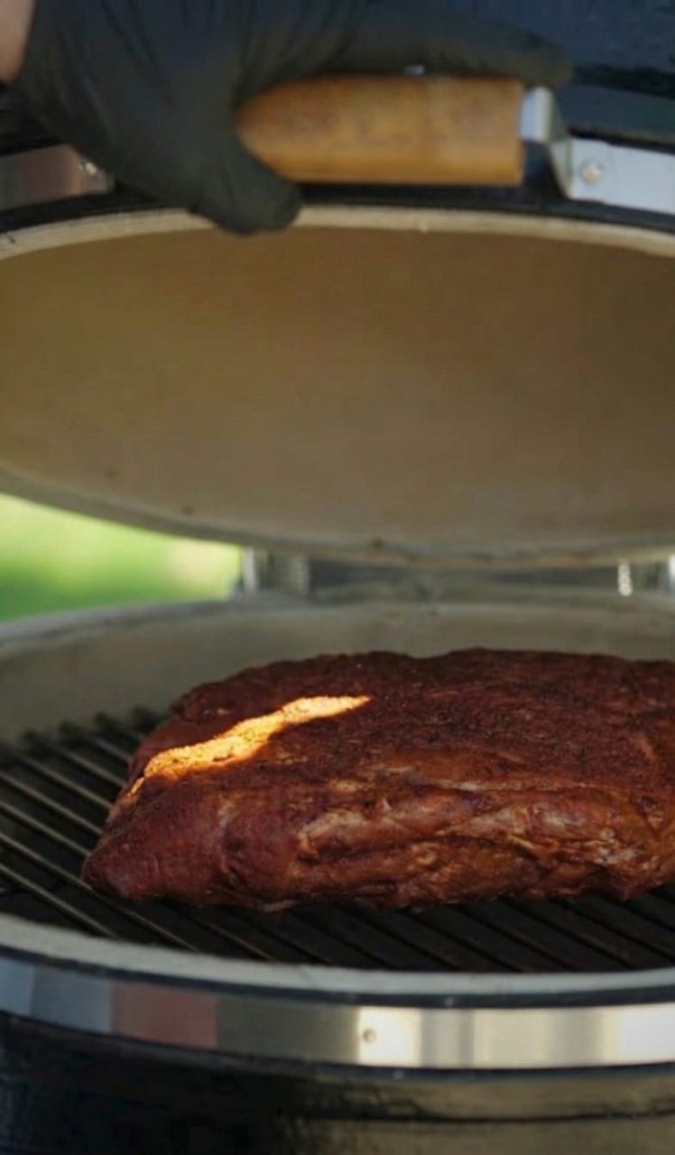 carne de cerdo ahumada sobre la parrilla en una barbacoa Kamado B10 color negro